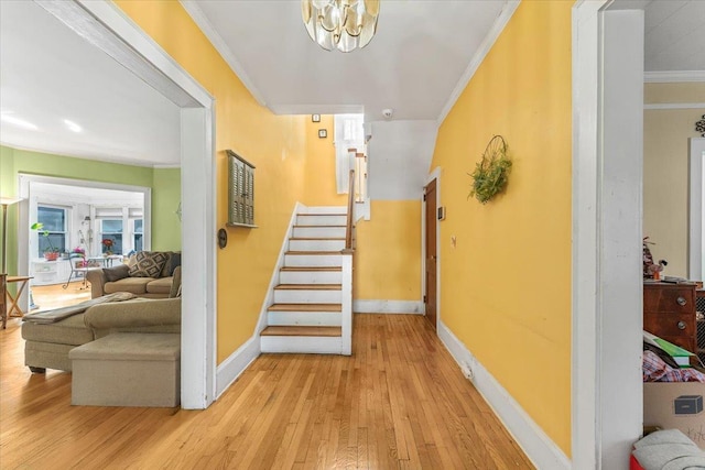 hallway with crown molding, an inviting chandelier, and light hardwood / wood-style flooring