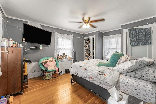 bedroom with hardwood / wood-style flooring, ceiling fan, and ornamental molding