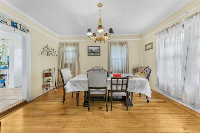 dining room with an inviting chandelier, ornamental molding, and light hardwood / wood-style flooring