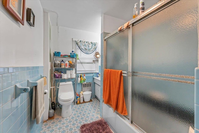 bathroom with toilet, combined bath / shower with glass door, and tile walls