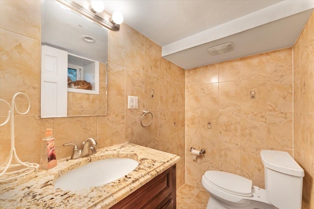 bathroom featuring tile walls, vanity, and toilet