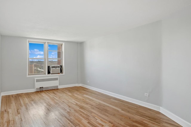 empty room with radiator heating unit, cooling unit, and light hardwood / wood-style flooring