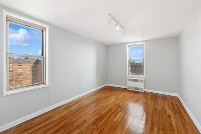 spare room featuring radiator, hardwood / wood-style floors, and track lighting