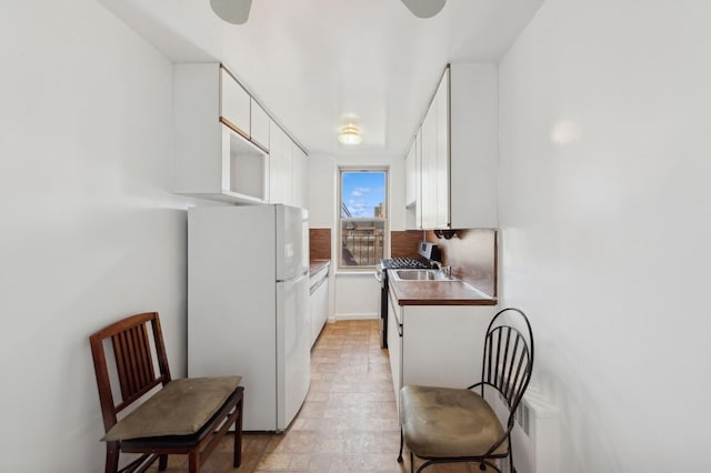 kitchen featuring white cabinets, white fridge, and sink