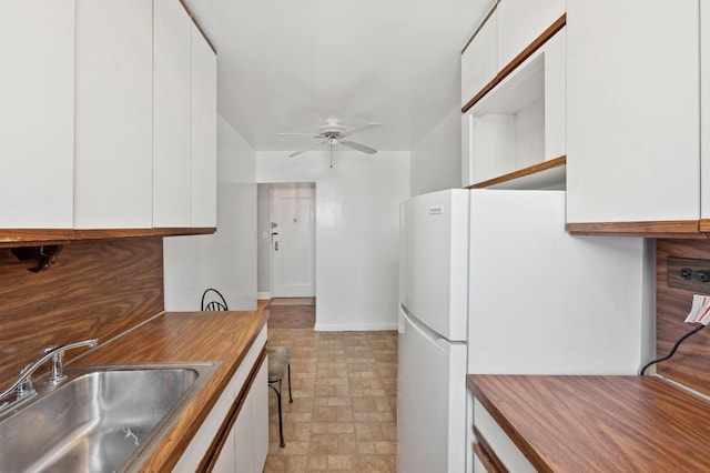 kitchen featuring white cabinets, white refrigerator, ceiling fan, and sink