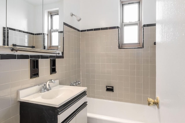 bathroom with vanity, a healthy amount of sunlight, tile walls, and tiled shower / bath