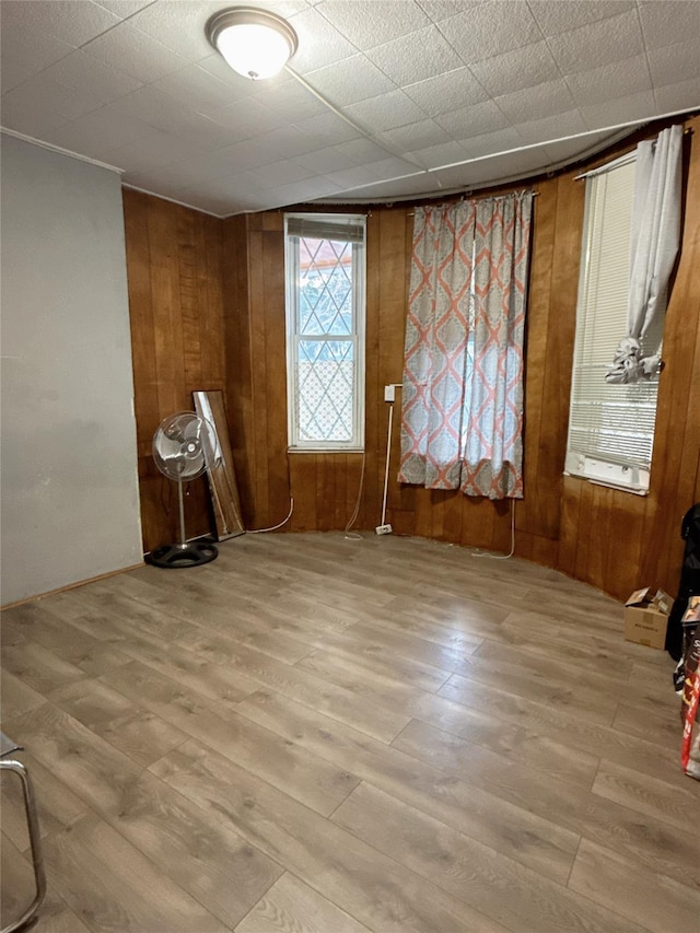 unfurnished room with wood walls and light hardwood / wood-style floors