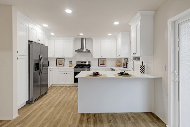 kitchen with wall chimney range hood, sink, light hardwood / wood-style floors, white cabinetry, and stainless steel appliances