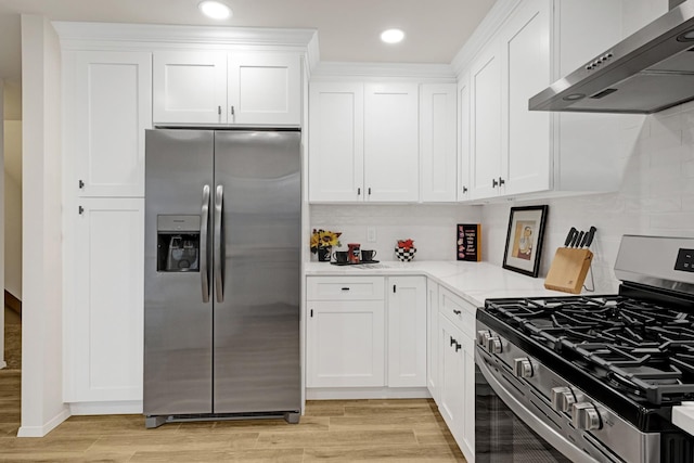 kitchen with wall chimney exhaust hood, white cabinetry, appliances with stainless steel finishes, and light hardwood / wood-style flooring