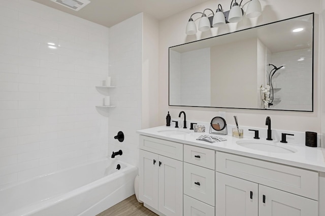 bathroom with wood-type flooring, vanity, and tiled shower / bath