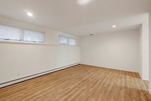 unfurnished room featuring light hardwood / wood-style floors and a baseboard heating unit