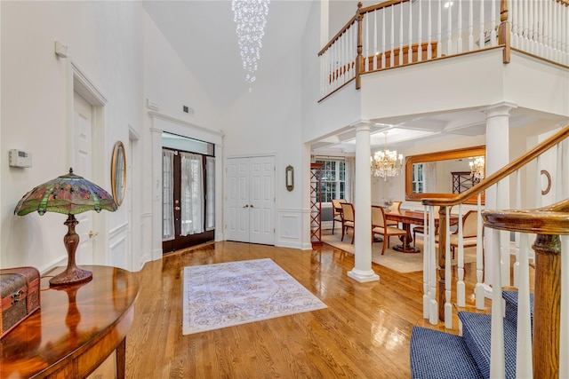 entryway featuring hardwood / wood-style floors, an inviting chandelier, ornate columns, and a high ceiling