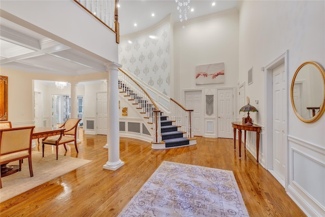 entrance foyer featuring coffered ceiling, light hardwood / wood-style flooring, ornate columns, ornamental molding, and beamed ceiling