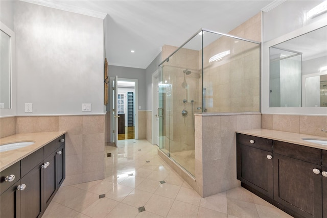 bathroom with crown molding, vanity, a shower with shower door, and tile walls