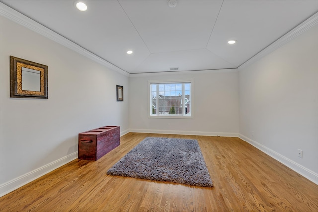 spare room featuring light wood-type flooring, vaulted ceiling, and crown molding