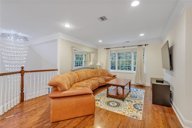 living room with light hardwood / wood-style flooring, an inviting chandelier, and ornamental molding