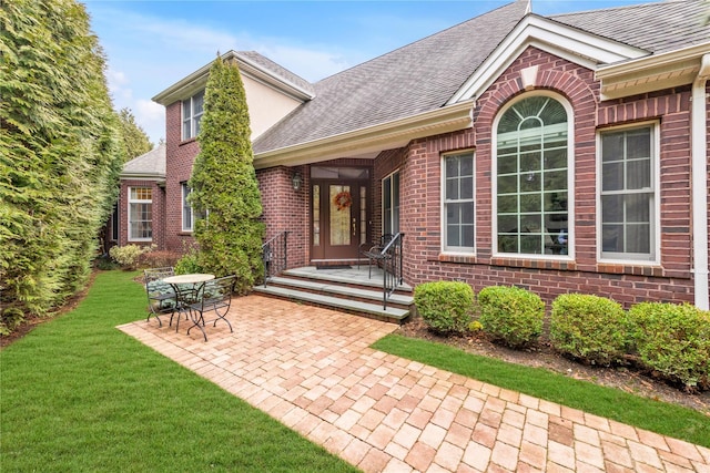 view of exterior entry with a yard and a patio