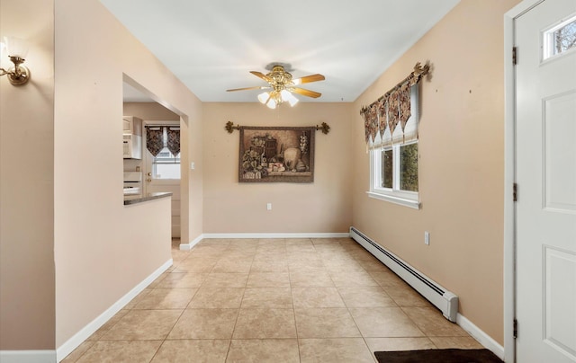 unfurnished room with ceiling fan, baseboard heating, and light tile patterned floors