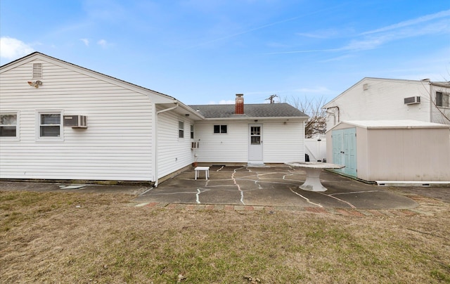 rear view of property featuring a lawn, a patio, a wall unit AC, and a storage shed