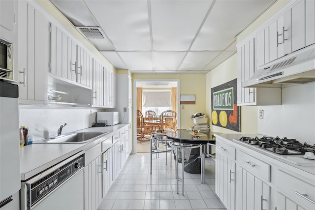 kitchen with white appliances, white cabinetry, a drop ceiling, and sink