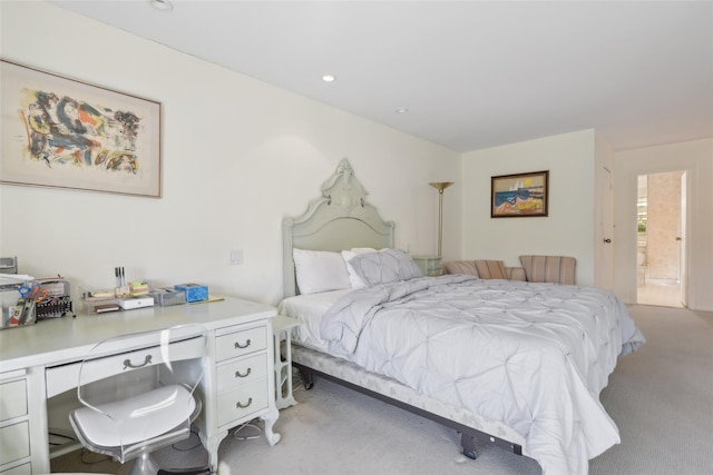 bedroom with ensuite bathroom and light colored carpet