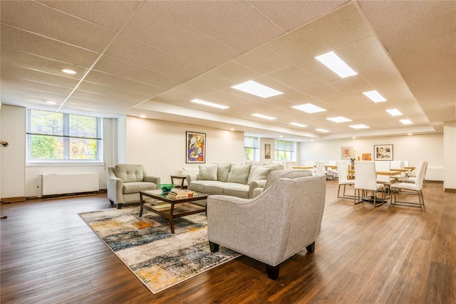 living room with radiator, hardwood / wood-style floors, and a drop ceiling