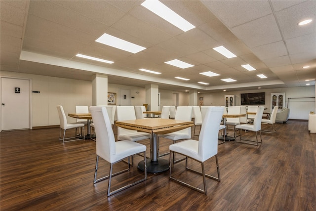 dining space featuring a paneled ceiling and dark hardwood / wood-style flooring