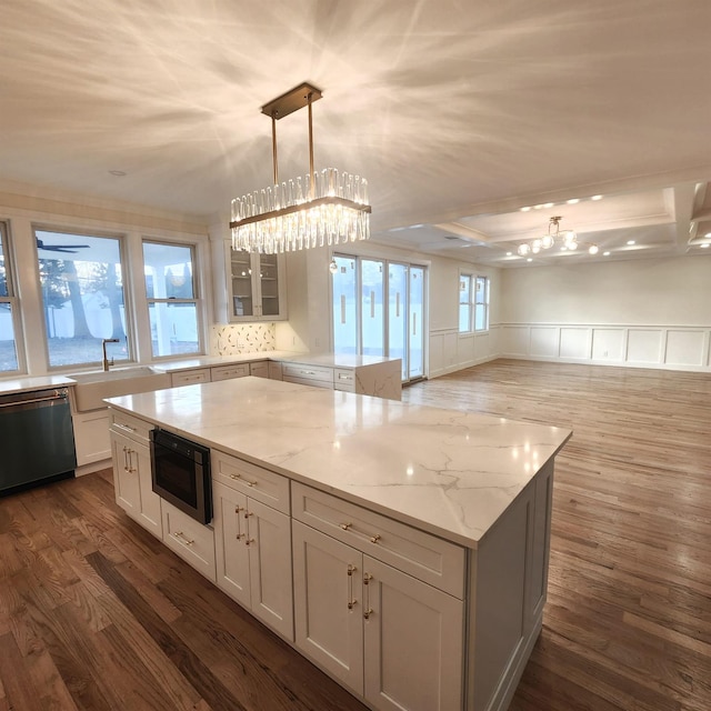 kitchen with black microwave, dishwasher, hanging light fixtures, light stone counters, and white cabinets