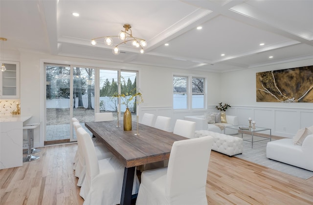 dining area with beamed ceiling, coffered ceiling, a chandelier, and light hardwood / wood-style flooring