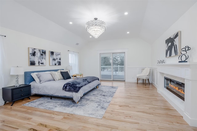 bedroom featuring lofted ceiling, a chandelier, access to outside, and light hardwood / wood-style floors