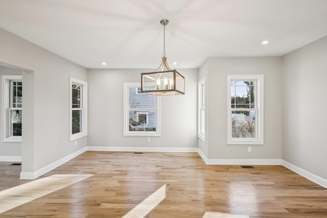 unfurnished dining area with a chandelier and light wood-type flooring