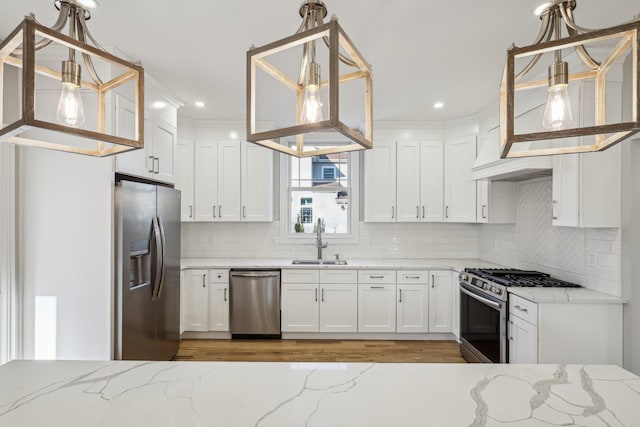 kitchen featuring light stone countertops, appliances with stainless steel finishes, sink, pendant lighting, and white cabinetry