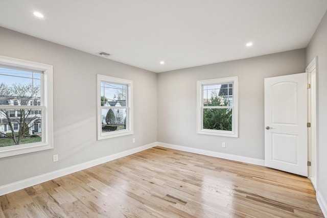 empty room with plenty of natural light and light hardwood / wood-style flooring