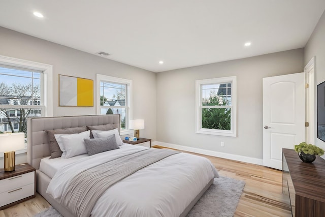 bedroom with multiple windows and light hardwood / wood-style flooring