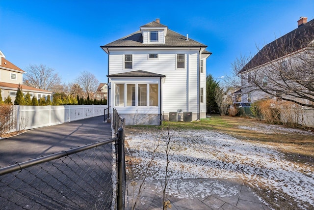 rear view of property featuring a sunroom and cooling unit