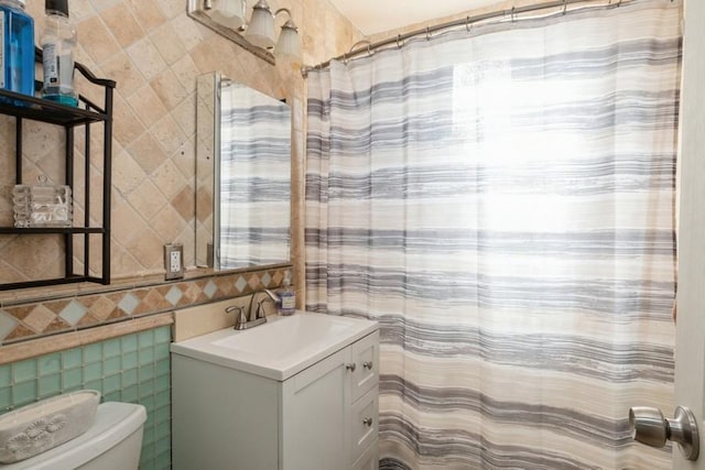 bathroom featuring vanity, toilet, and tile walls