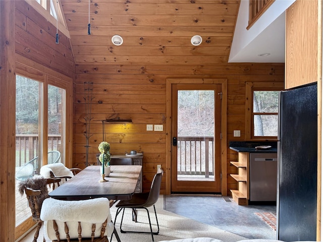 dining space with vaulted ceiling, wooden ceiling, and wood walls