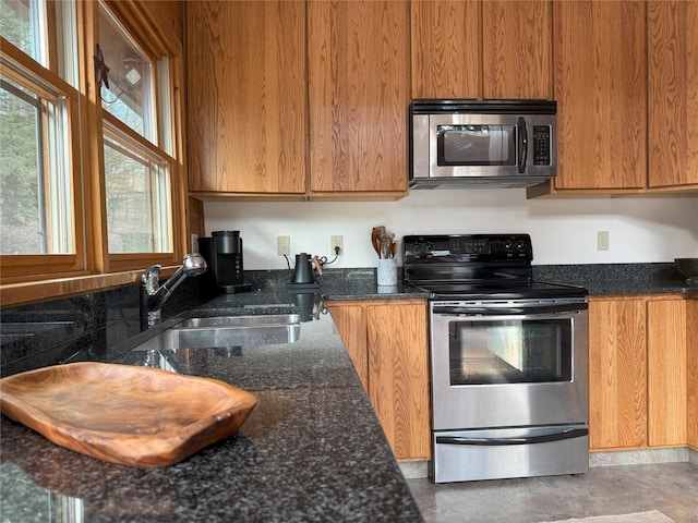 kitchen featuring sink, stainless steel appliances, and dark stone counters