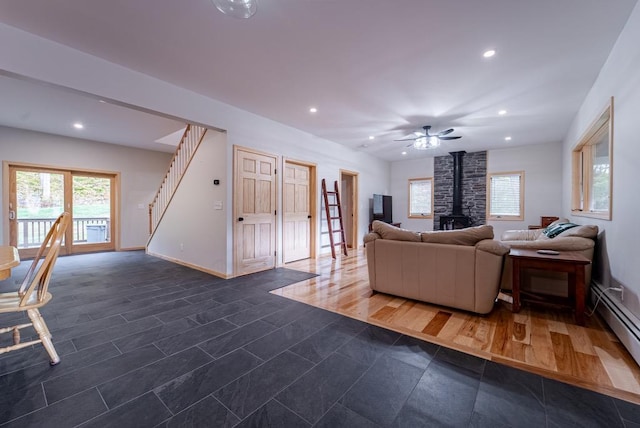 living room featuring a wood stove, ceiling fan, and a baseboard radiator