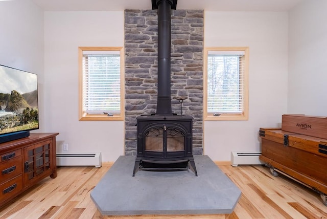 living room with light wood-type flooring, a wood stove, and baseboard heating