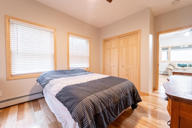 bedroom with multiple windows, a closet, light hardwood / wood-style floors, and a baseboard radiator