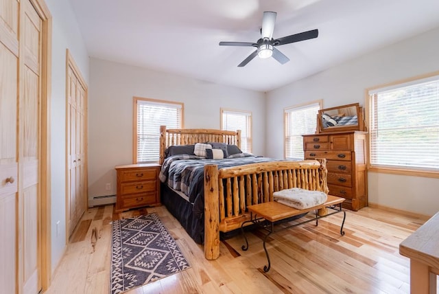 bedroom featuring ceiling fan, light hardwood / wood-style flooring, and a baseboard heating unit