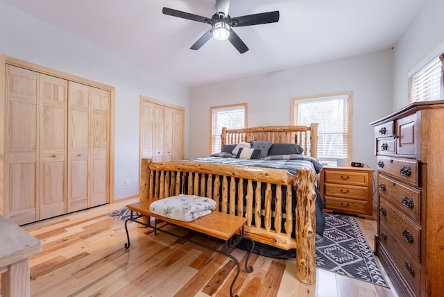 bedroom with multiple closets, ceiling fan, and light wood-type flooring