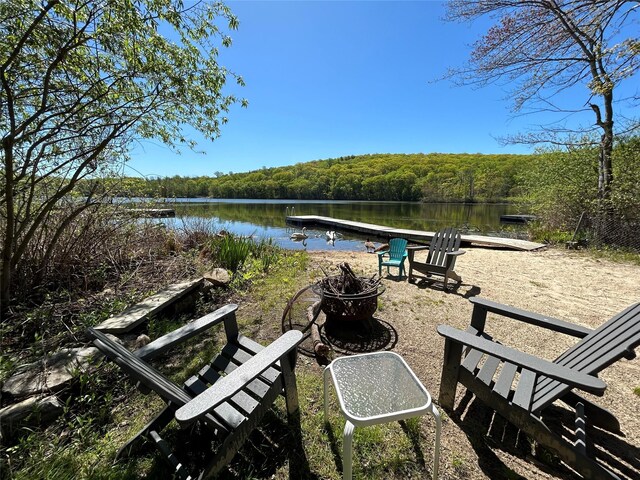 view of home's community with a forest view, an outdoor fire pit, and a water view