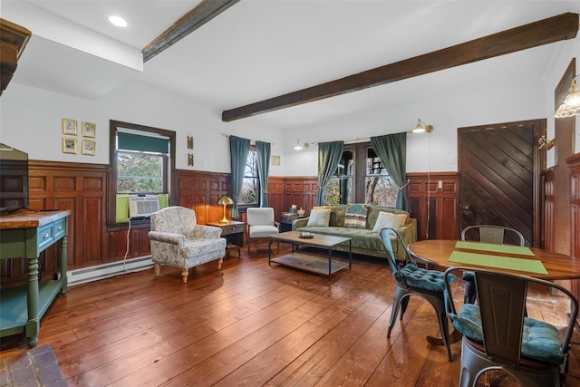 living area with wainscoting, hardwood / wood-style flooring, beamed ceiling, baseboard heating, and cooling unit