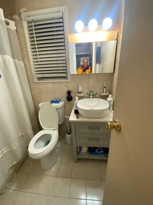 bathroom with toilet, vanity, tile patterned floors, and tile walls