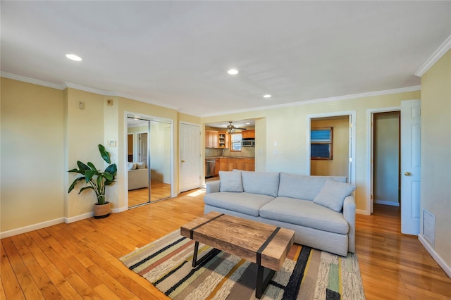 living room featuring ceiling fan, light hardwood / wood-style floors, and crown molding