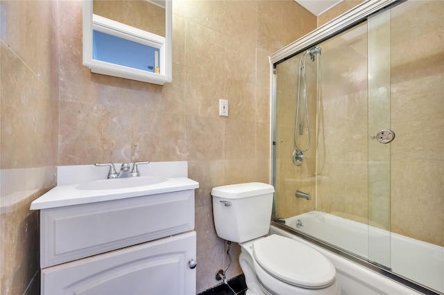 full bathroom featuring tile walls, enclosed tub / shower combo, vanity, and toilet