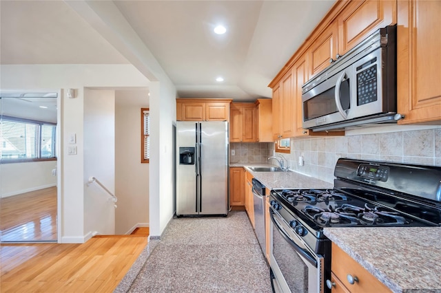 kitchen featuring sink, light wood-type flooring, backsplash, and appliances with stainless steel finishes