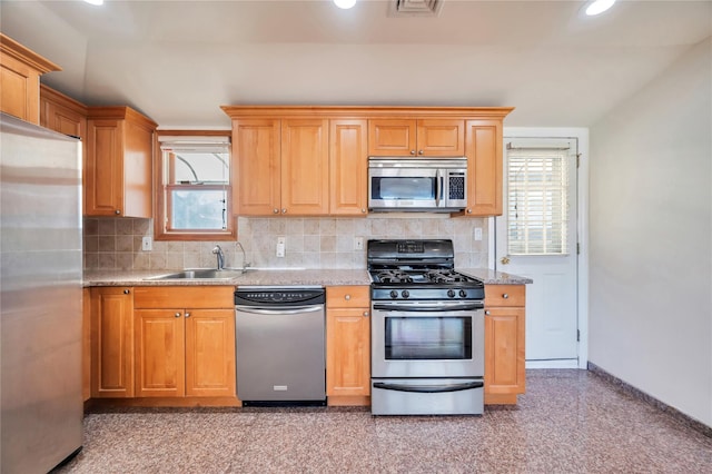 kitchen featuring stainless steel appliances, sink, tasteful backsplash, and light stone countertops